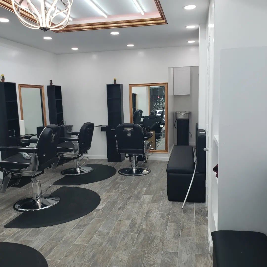 Empty barber stations with black chairs, round floor mats and wide mirrors